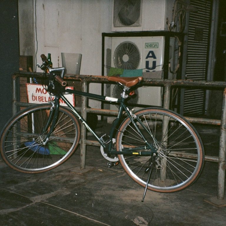 Werkstatt 7 Schwarzes Fahrrad mit braunem Sattel, neben einer Wand mit Klimaanlage.