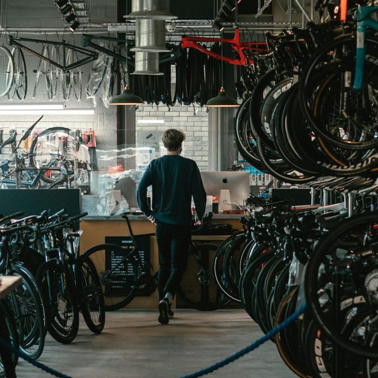 Werkstatt 7 Person in einem Fahrradgeschäft zwischen vielen Fahrrädern und Werkstattbereich.